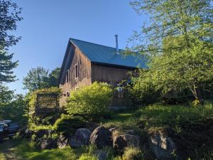 Um velho celeiro com pedras à frente. em Cottage Jacques Cartier em Stoneham