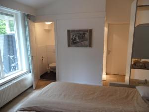 a bedroom with a bed and a window and a bathroom at B&B Cantecleer Vught in Vught