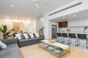 a living room with a gray couch and a kitchen at Foam in Byron Bay