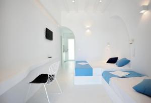 a white room with two beds and a chair at Beba's Studios in Batsi