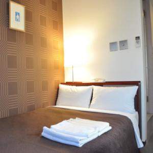 
a hotel room with a bed and a lamp at Hotel Select Inn Nagano in Nagano
