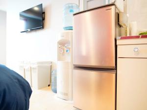 a stainless steel refrigerator in a kitchen with water bottles at Mcity in Furujima in Naha