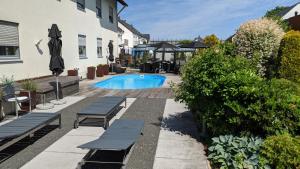 a swimming pool with two benches next to a building at Hotel Rotes Ross in Erlangen