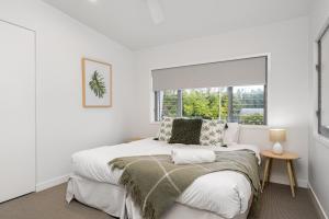 a white bedroom with a bed and a window at Foam in Byron Bay +20 photos