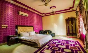 a bedroom with pink walls and a bed and a couch at Arabian Lodges in Bahawalpur