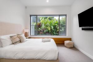 a bedroom with a large white bed and a window at Foam in Byron Bay