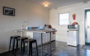 a kitchen with a sink and stools in it at Mangonui Motel in Mangonui
