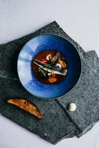 a blue bowl of food on a plate on a table at Lapland Hotels Kilpis in Kilpisjärvi