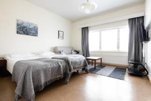 a white bedroom with a bed and a window at Lapland Hotels Kilpis in Kilpisjärvi