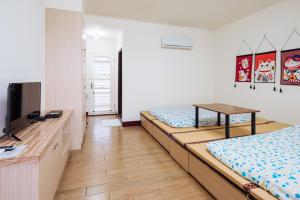 1 dormitorio con 2 camas, TV y mesa en Urarakana B&B en Gongguan