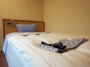 a white bed with two towels on top of it at 大村ヤスダオーシャンホテル in Omura