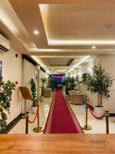 a lobby with a red carpet and potted plants at روز للشقق الفندقية 2 in Al Kharj