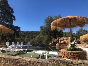 - un groupe de chaises et un parasol à côté de la piscine dans l'établissement Casa Rural Monterrey Aroche, à Aroche