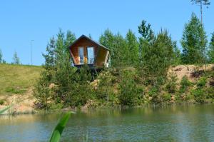 a house on a hill next to a body of water at Metsjärve mini puhkemaja in Põlva