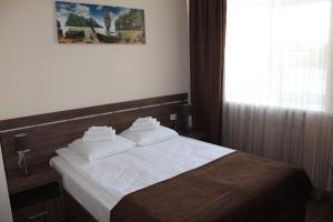 een slaapkamer met een bed met witte lakens en een raam bij Гостиница ОКА in Kaloega