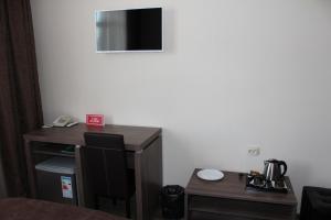 een kamer met een bureau, een tafel en een televisie bij Гостиница ОКА in Kaloega