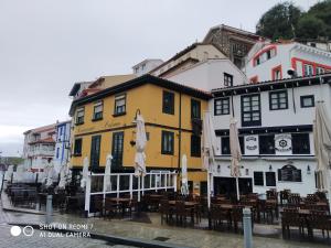 a yellow and white building with tables and umbrellas at Hotel Sol de la Blanca in Cudillero