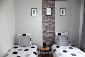 two twin beds in a room with a brick wall at ESCALE À ÉPERNAY APPT 2/4 PERS AUX BORDS DE MARNE in Épernay +9 photos