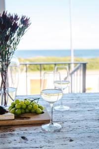 due bicchieri da vino seduti su un tavolo con uva di Skoon Seaside Accommodation a Skoenmakerskop