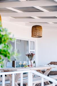 a dining room table with wine glasses and a light fixture at Skoon Seaside Accommodation in Skoenmakerskop