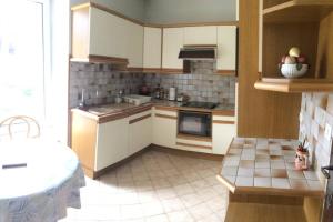 eine Küche mit weißen Schränken und einem Fliesenboden in der Unterkunft Appartement spacieux 78m2 plein centre, balcon, jusqu’à 6 personnes in La Bourboule + 3 Fotos