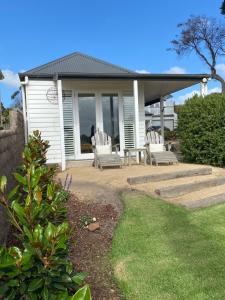 Casa blanca con 2 sillas y mesa en Mt Martha Villas, en Mount Martha