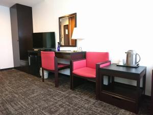 札幌市にあるホテルブーゲンビリア札幌のデスク、椅子2脚、テレビが備わるホテルルームです。