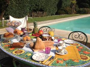 Relais di Alice- Adults Only في فورتي دي مارمي: طاولة مع افطار من خبز وفواكه بجانب مسبح