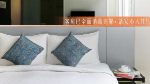a bed with blue and white pillows on it at CityInn Hotel Plus - Taichung Station Branch in Taichung