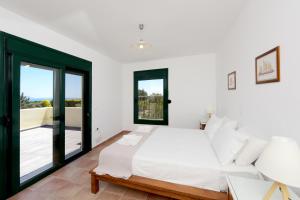 - une chambre blanche avec un lit et un balcon dans l'établissement Seaside Villa, à Gennadi