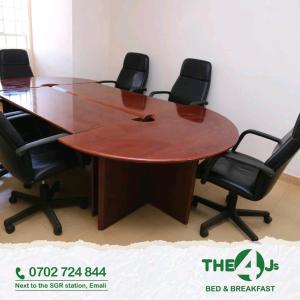 una sala de conferencias con mesa de madera y sillas en The 4 JS Bed and Breakfast Emali, en Emali