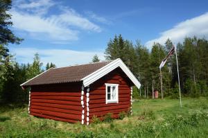 a small log cabin in a field with a flag at Hytte fra 1721 uten internett, strøm, vann - men med rødmalt utedo in Ljørdal