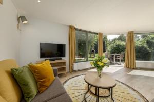 a living room with a couch and a table with a vase of flowers at Center Parcs De Eemhof in Zeewolde