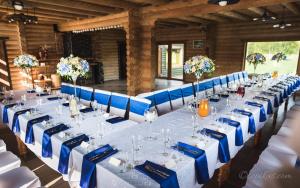 a long table with blue chairs and white tables at Minavuonė in Telšiai