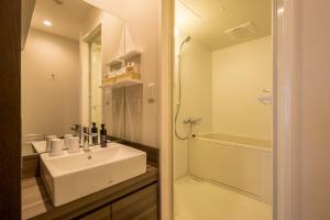 a white bathroom with a sink and a shower at HOTEL R9 Kujukuri "ex Casual Resort COFF Ichinomiya" in Ichinomiya