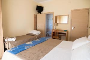 a hotel room with two beds and a desk at Hotel Cormoran Riccione in Riccione