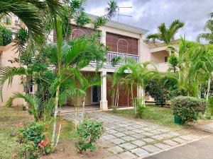 a house with palm trees in front of it at Beachfront Villa in a beautiful and secured complex in Flic-en-Flac