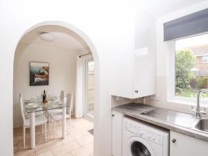 a white kitchen with a table and a sink at Tidal Drift in Weymouth