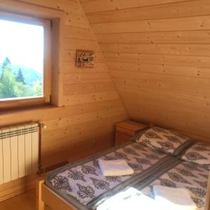 a bed in a log cabin with a window at Bacówka Szlembark in Szlembark