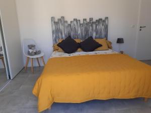 a bedroom with a large bed with a yellow bedspread at jardin zen in La Londe-les-Maures