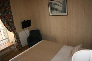 a bedroom with a bed and a chair and a television at Hôtel Le D'Avaugour in Dinan