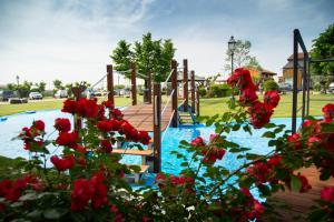 un parque infantil con tobogán y flores rojas en NIDO DEL GELSO en Verona