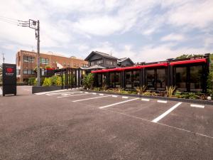 an empty parking lot with a red building at HOTEL R9 Kujukuri "ex Casual Resort COFF Ichinomiya" in Ichinomiya