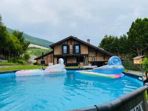 a swimming pool with two inflatables in front of a house at BARANDI URBASA CASA RURAL in Olazagutía