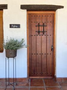 eine Holztür mit einer Topfpflanze davor in der Unterkunft The Wild Olive Andalucía Palma Guestroom in Casares