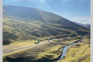a person riding a bike on a road on a hill at Glendyne Cottages, Highest Village in Scotland in Wanlockhead