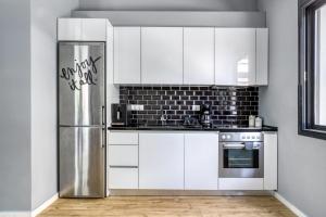 kuchnia z białymi szafkami i lodówką ze stali nierdzewnej w obiekcie Spacious flat with courtyard in Peristeri! w Atenach