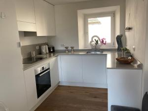 a kitchen with white cabinets and a sink and a window at ON the RAIL by Arcotrilogy-Homes in Arco