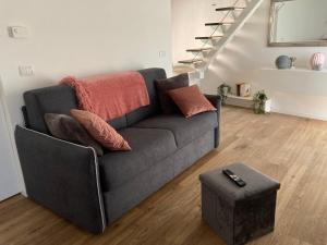 a living room with a gray couch with pillows and a stool at ON the RAIL by Arcotrilogy-Homes in Arco