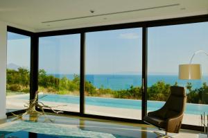 a living room with a chair and a view of the ocean at PRIVE The Luxury Villa & Boutique Hotel, Cape of Rodon in Draç